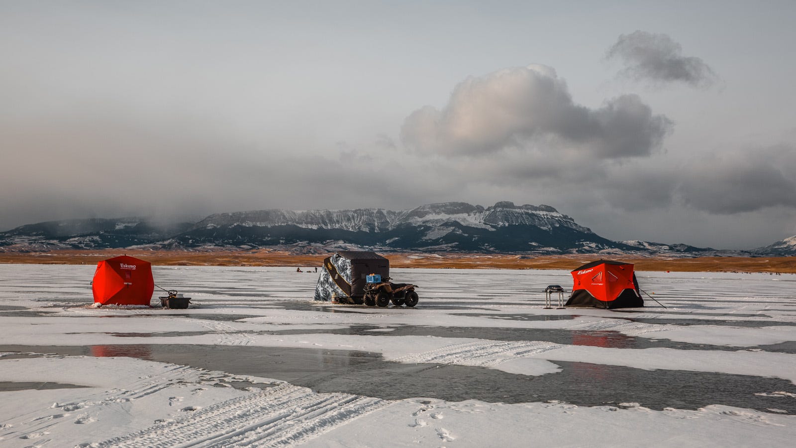Three ice fishing huts spread across the ice