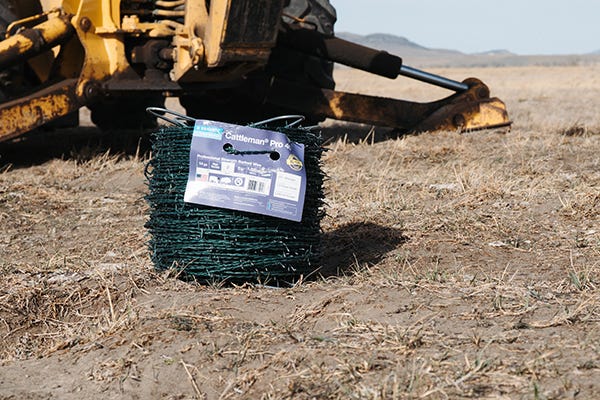 Roll of barbed wire sitting in pasture.