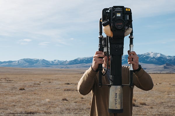 Rancher using Titan Post Driver on a t-post with a mountain scene in the back