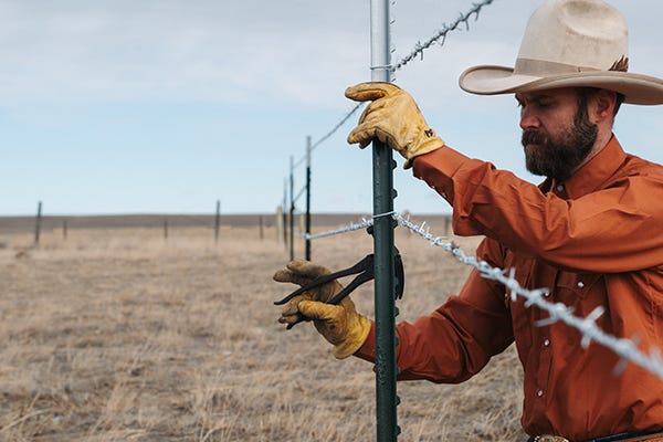 Rancher fixing a barbed wire fence post in an open pasture with the headline ‘Stop Fixing Fence'.