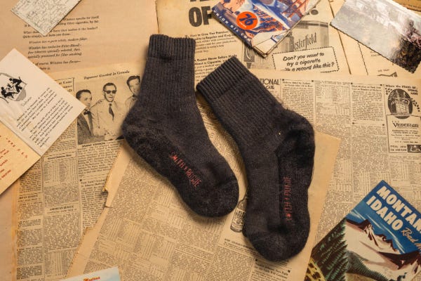 Grey Socks with orange lettering laying on newspaper and maps