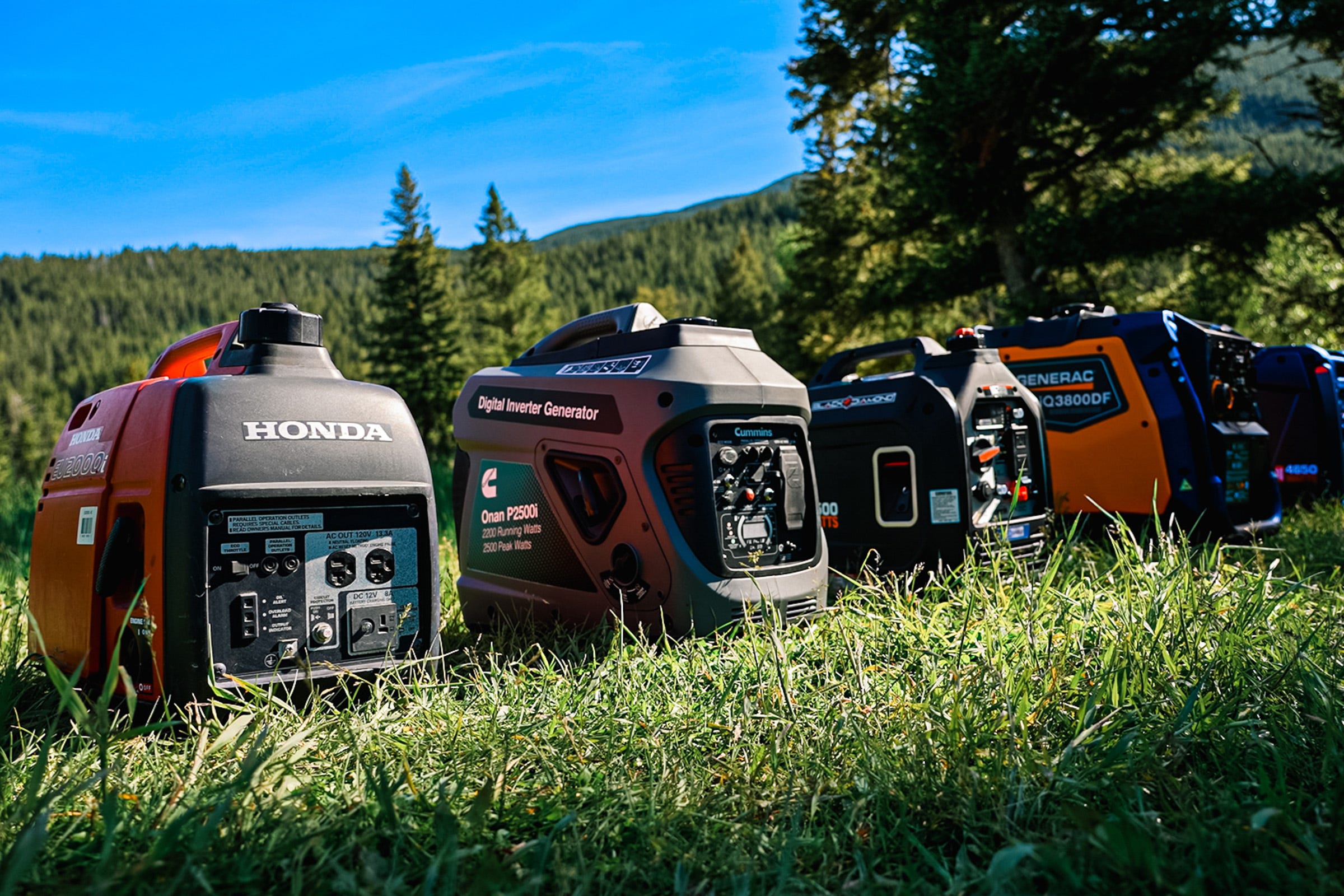 Portable inverter generators from Honda, Cummins Onan, Generac, and Black Diamond displayed on grass in a mountain campsite setting, illustrating generator options for RV and camper power needs.