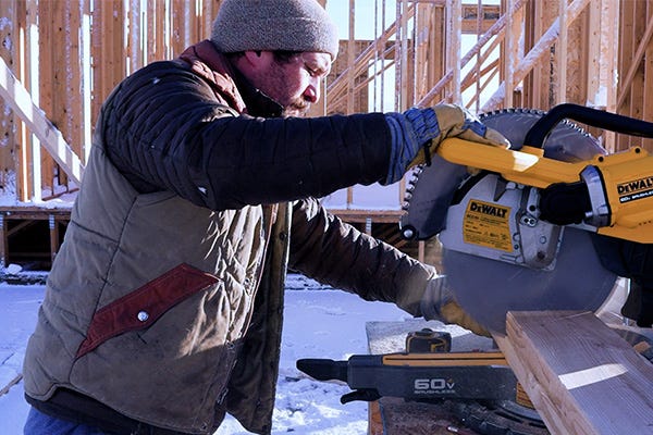 Cutting framing lumber with a cordless DeWalt miter saw during residential construction