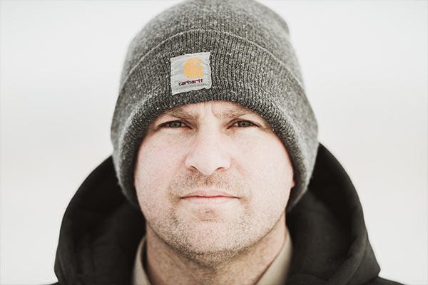 Close up of a man wearing a Carhartt beanie with a background of snow