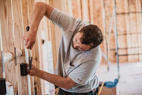 A man works inside a home being built while wearing a Carhartt t-shirt