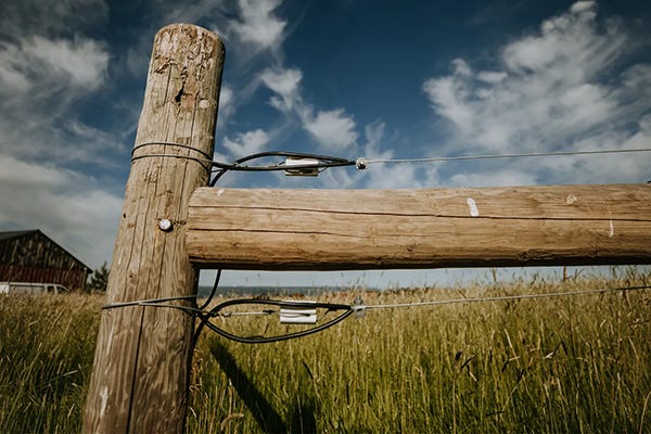 An h-brace of a fence in a field with tall grass