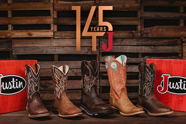 A selection of different Justin boots lined up on a wood table with wood background