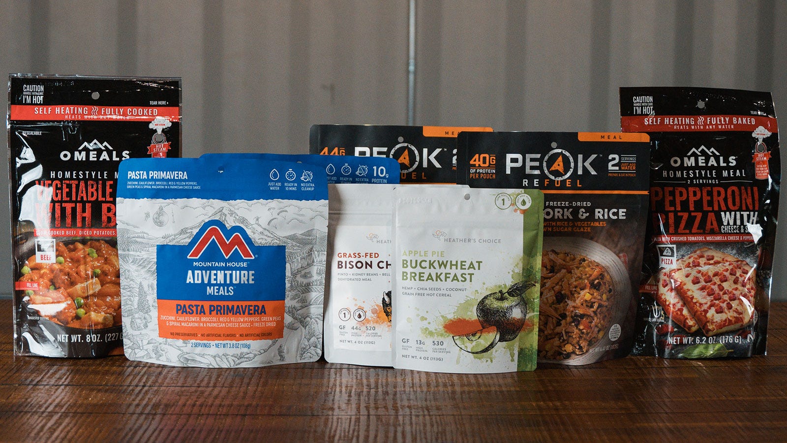 Testing Eight Camp Meals Text with Camp Meals by Peak, OMEALS, Mountain House, Heather's Choice on top of a table. 