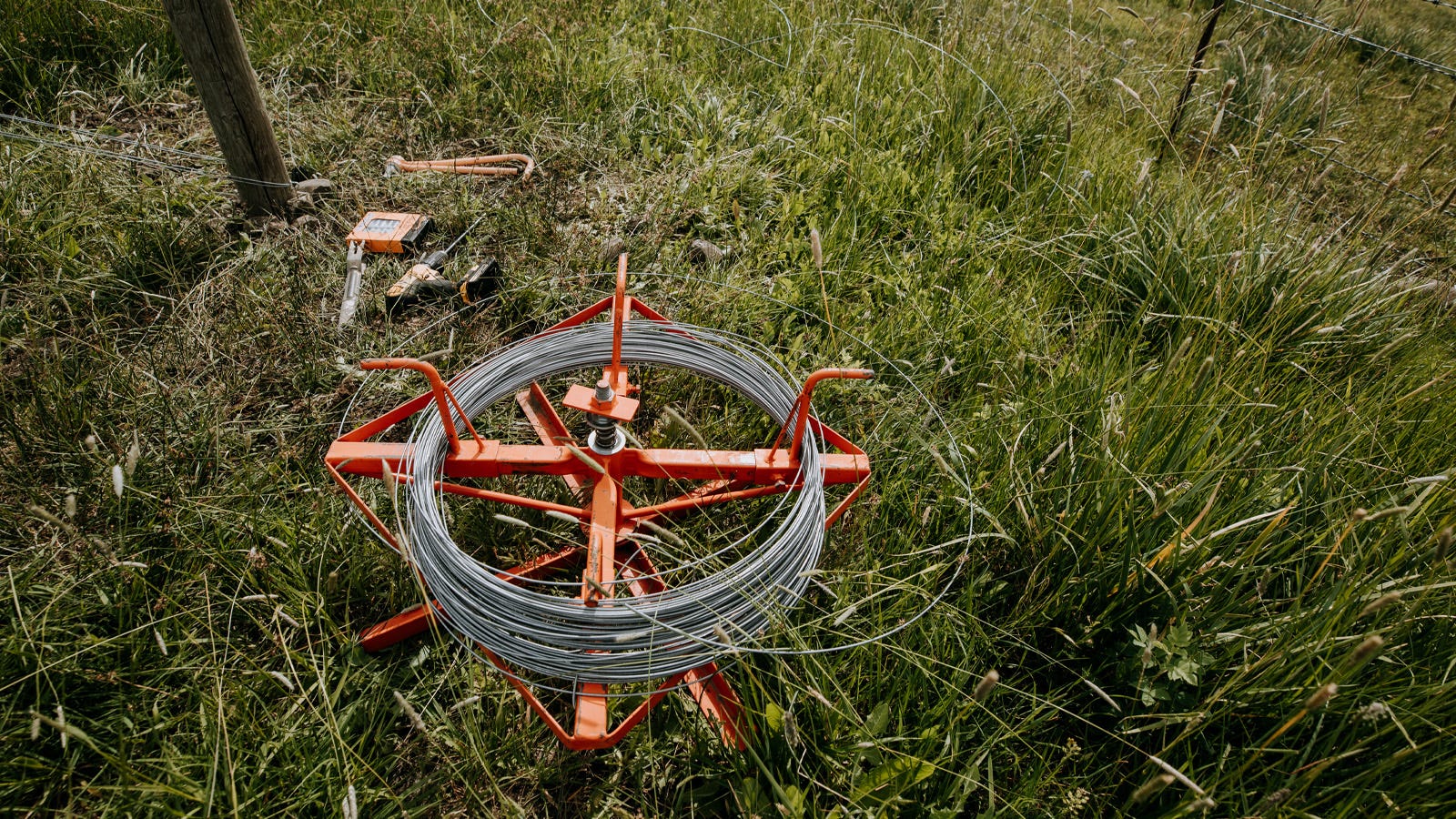 A roll of galvanized wire laying in the grass 