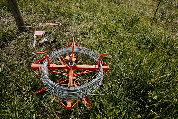 A roll of galvanized wire laying in the grass 
