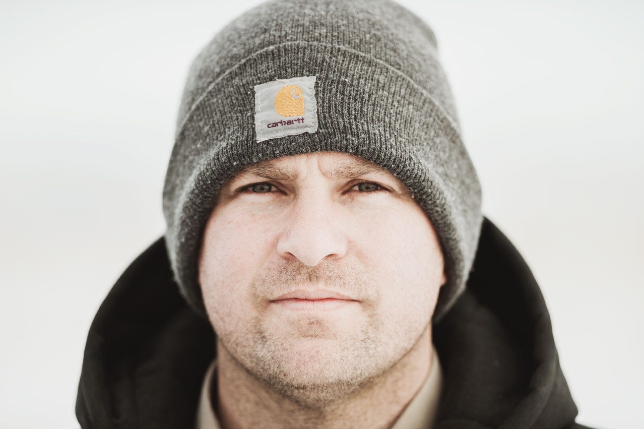 Close up of a man wearing a Carhartt beanie with a background of snow