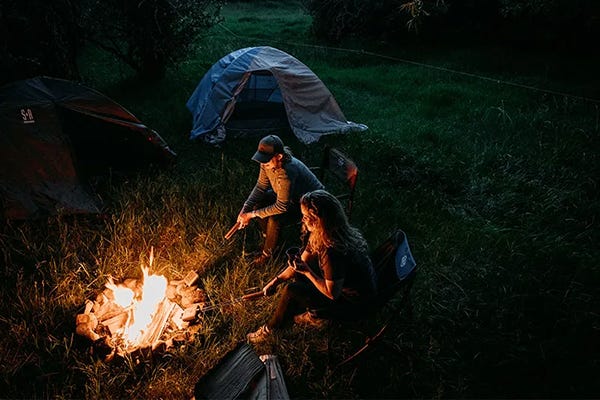 Two people sitting around a fire at a campsite