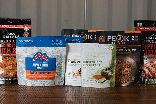 Testing Eight Camp Meals Text with Camp Meals by Peak, OMEALS, Mountain House, Heather's Choice on top of a table. 