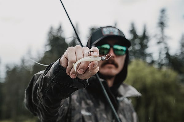 fishing on a boat, holding up a small swimbait on a jig head with a rod in my hand