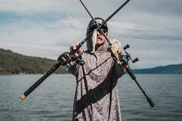 holding up two swate swimbait rods in an X, a megabass magdraft hanging, and a throwback bait rigged up, with a shimano curado and daiwa lexa reel