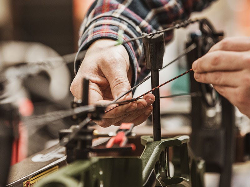 The hands of a North 40 bow tech tuning a bow