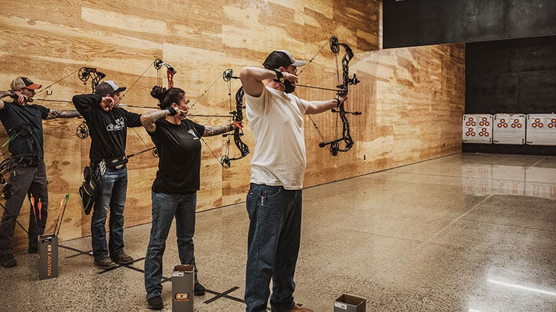 Four archers draw their bows at the North 40 indoor archery range