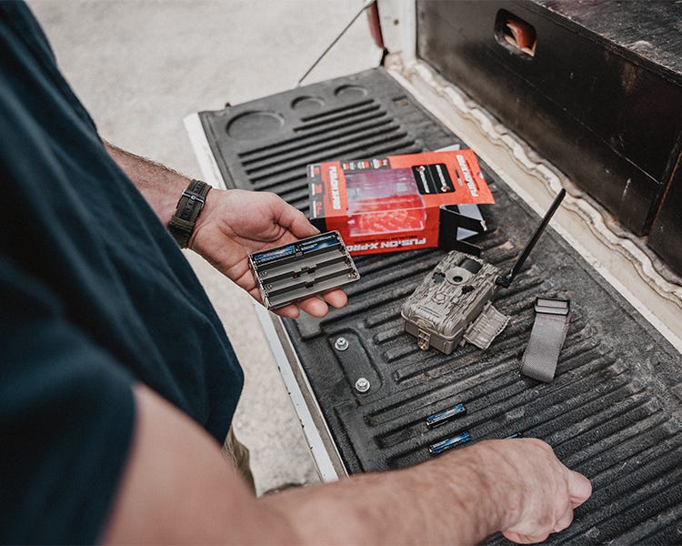 Taking a brand new stealth cam game camera out of the box on the tailgate of the truck, putting in durastart batteries to get ready and set it