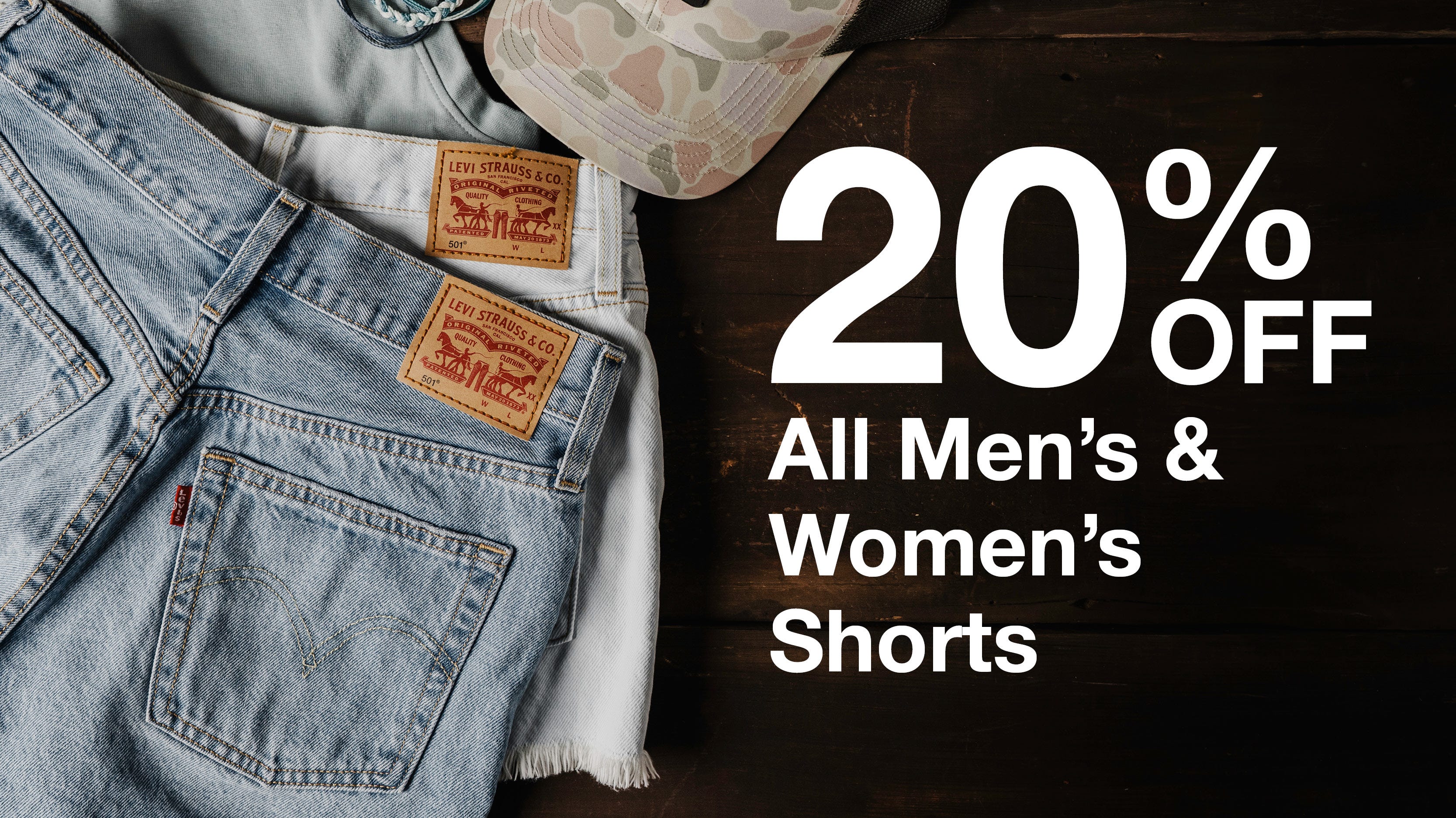 Text reads "20% Off All Men's and Women's Shorts" Background shows a flat lay of two denim shorts.