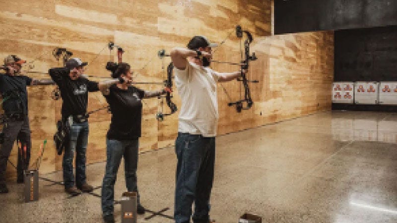 Three archers draw their bows at the indoor rang in North 40 Outfitters