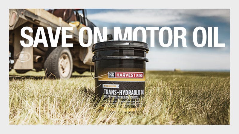 Harvest king motor oil stand alone in grass with truck behind