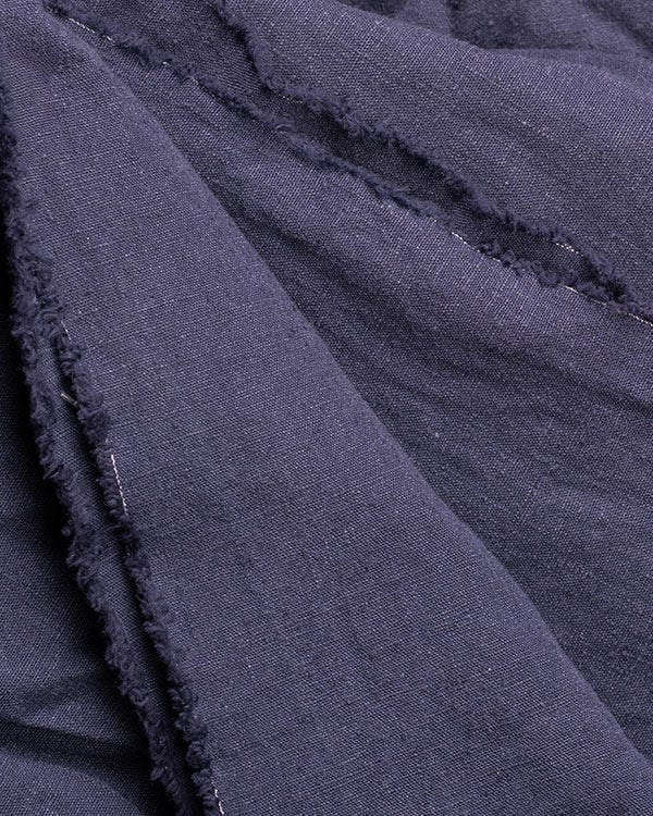 Close-up of folded dark hemp fabric showing textured weave and unfinished edges.