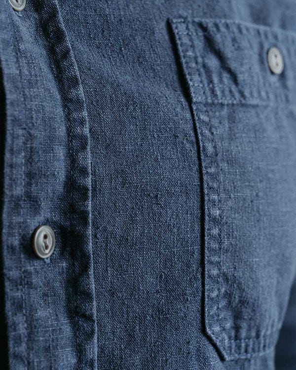 Close-up of dark blue hemp fabric shirt showing buttons, stitching, and front chest pocket details