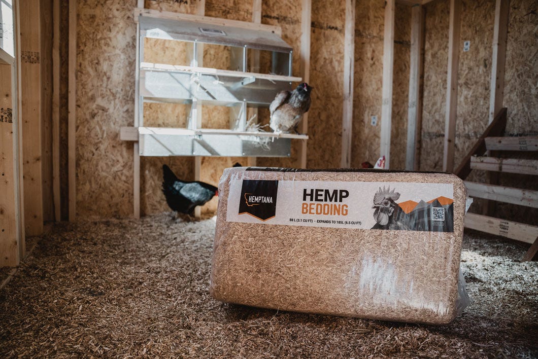 An unopened package of Hemptana bedding sitting in a chicken coop with two chickens in the background