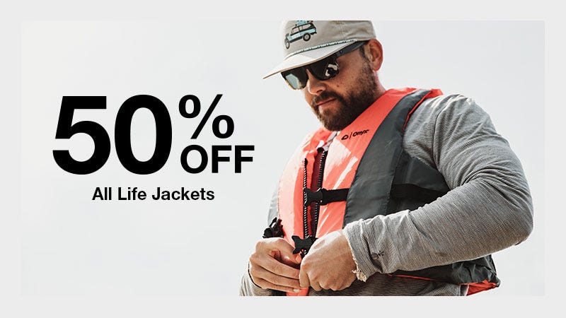 A man wearing a life jacket stands next to a sign that reads "50% off all life jackets."