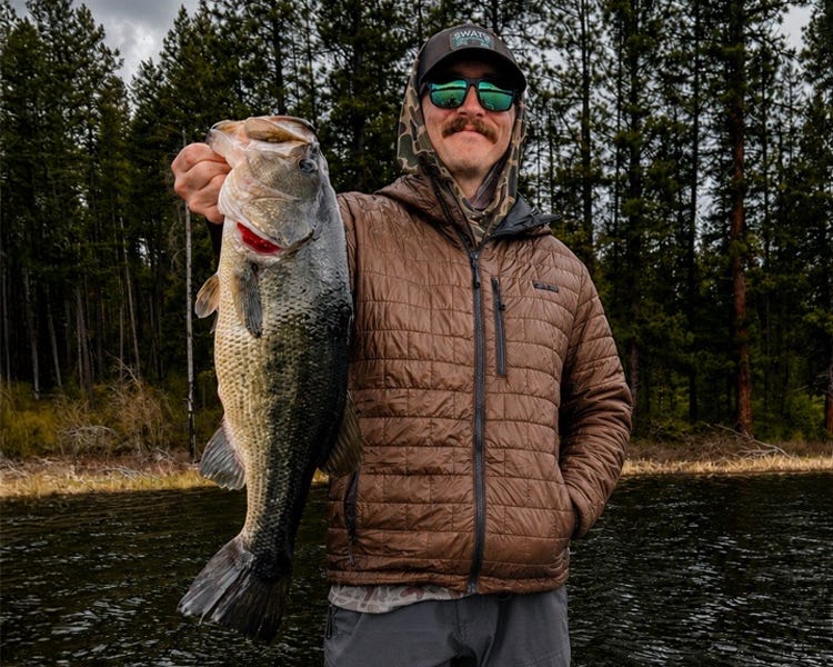 standing on the deck of the boat, on a cold brisk morning, holding up an almost 7lb largemouth bass