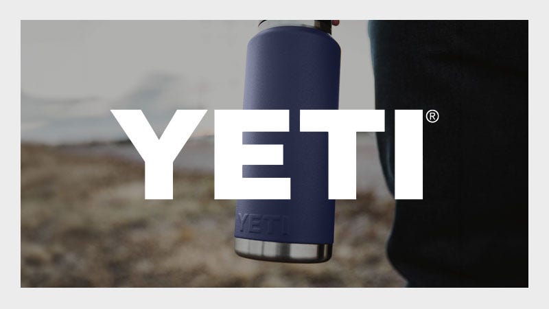 A person holding a blue Yeti insulated bottle outdoors with the large white "YETI" logo overlaid across the center of the image.