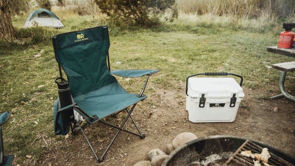 An Outdoor Revival chair sits next to an Outdoor Revival cooler an a firefit
