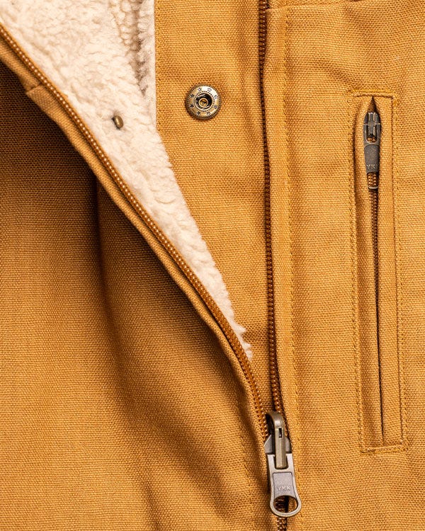 Close-up of Smith + Rogue original canvas jacket featuring durable tan canvas material, sherpa-lined interior, front zipper closure, and vertical zip chest pocket with metal hardware.