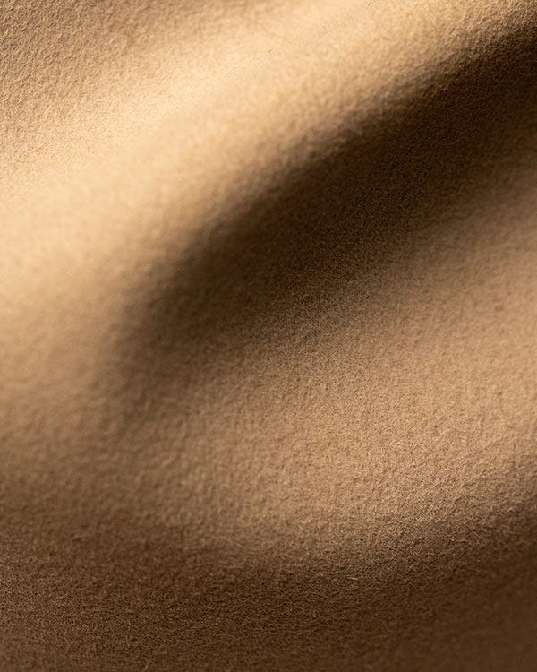 Close-up view of tan felt fabric of a cowboy hat showing a soft, textured surface with gentle folds.
