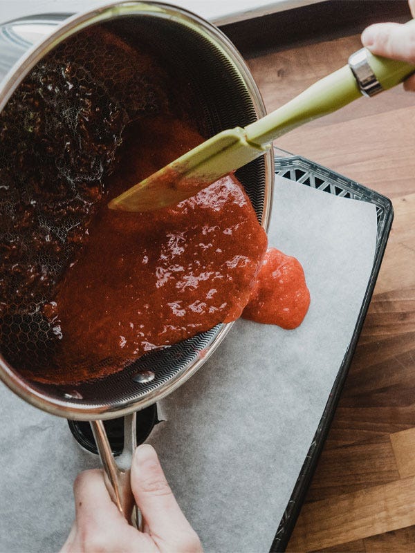 Pouring the strawberry fruit leather mixture onto parchment paper