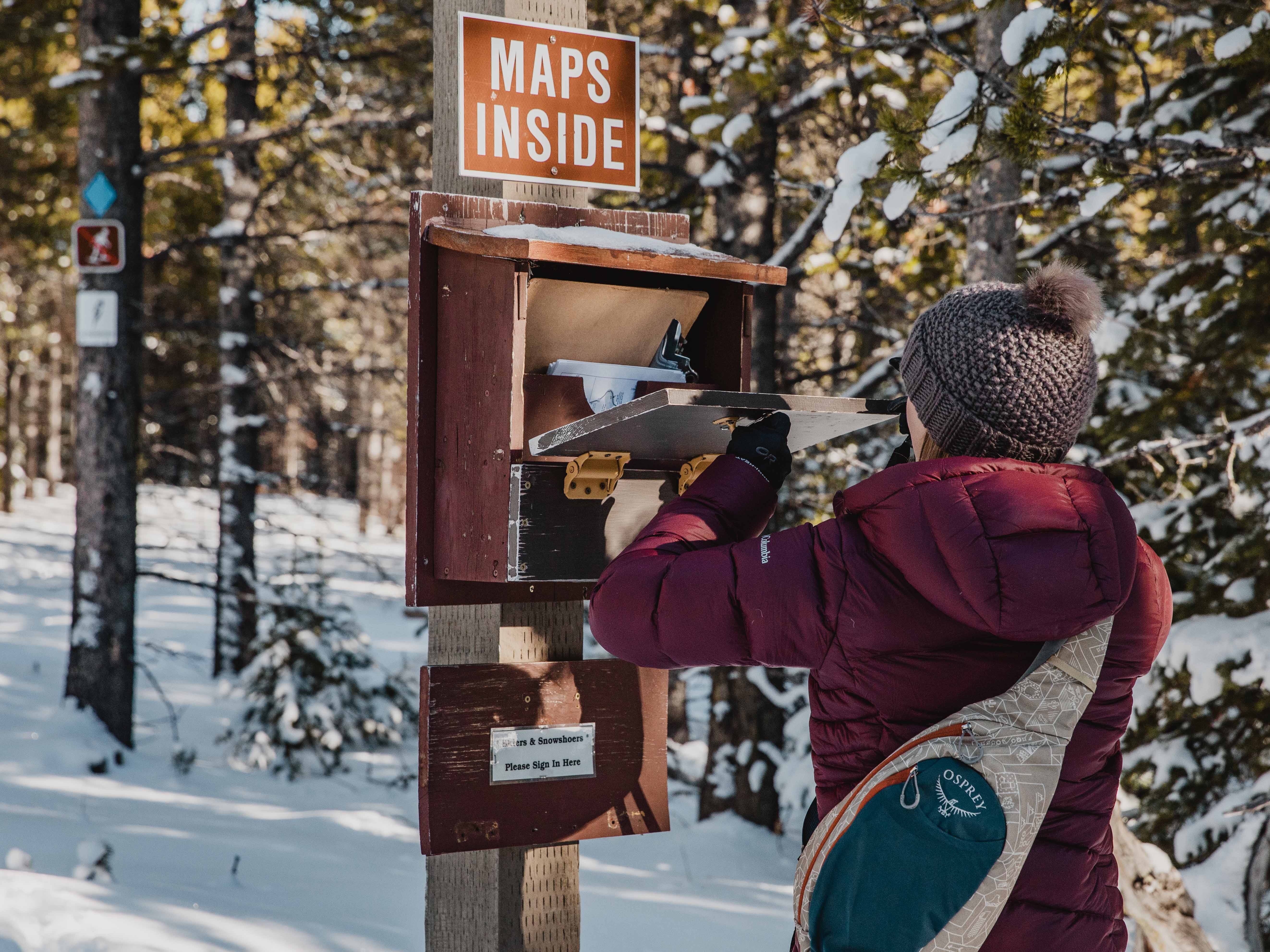 a women checks a map container on a snowshoeing trail