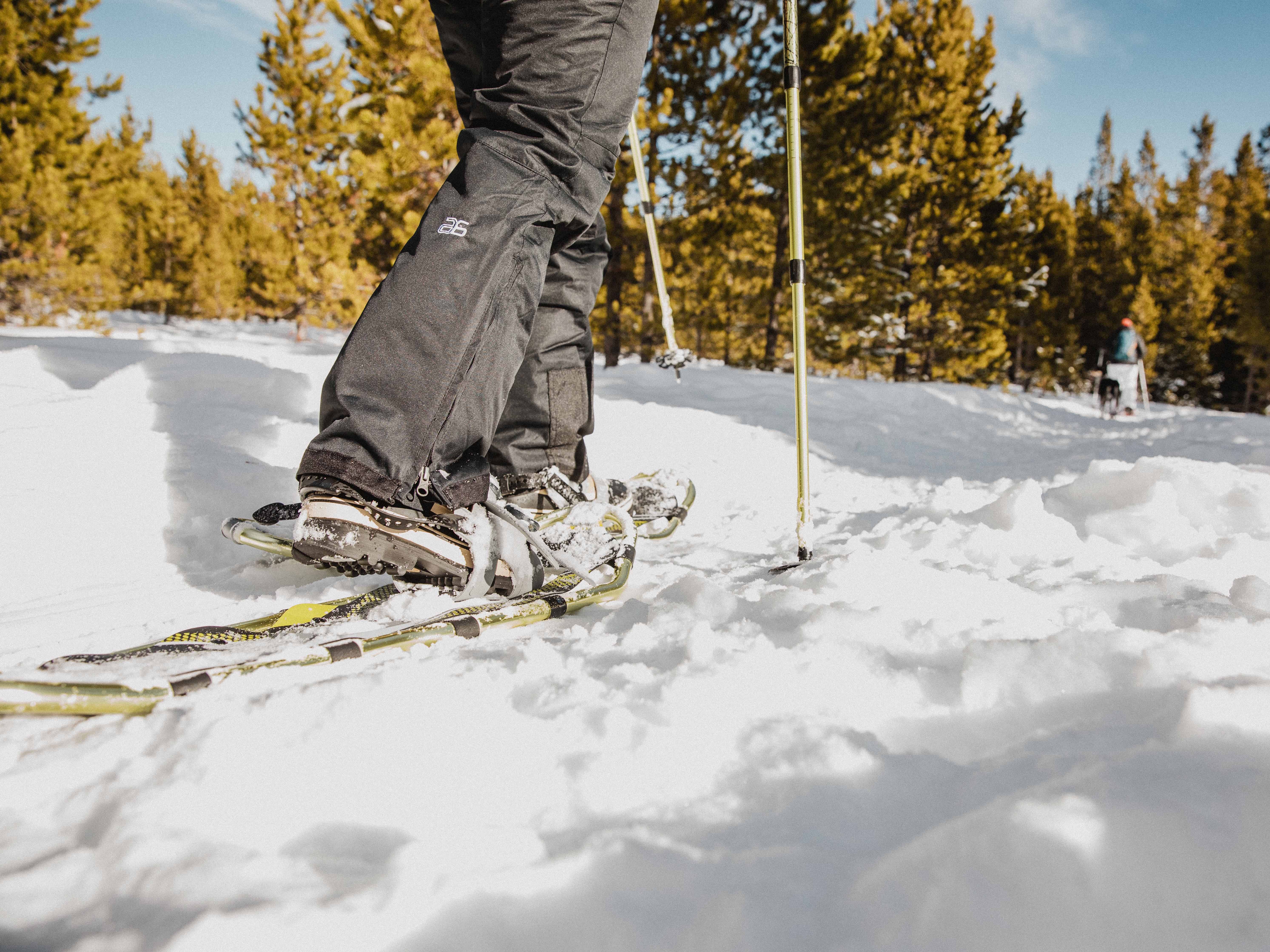 a women snowshoes on a brightly lit winter days