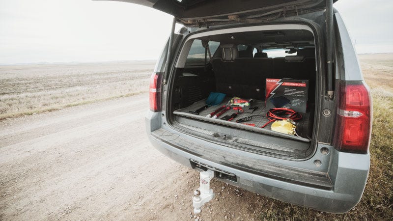 in the winte, an SUV back hatch is open revealing a trunk full of safety equipment