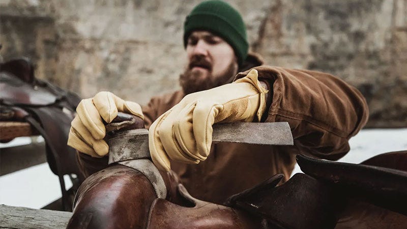 man wearing leather glves putting on saddle