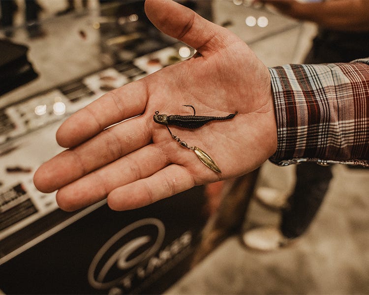 Great Lakes Finesse Drop Tail Minnow rigged on a micro underspin, placed on a tackle tray with finesse gear at ICAST fishing trade show.