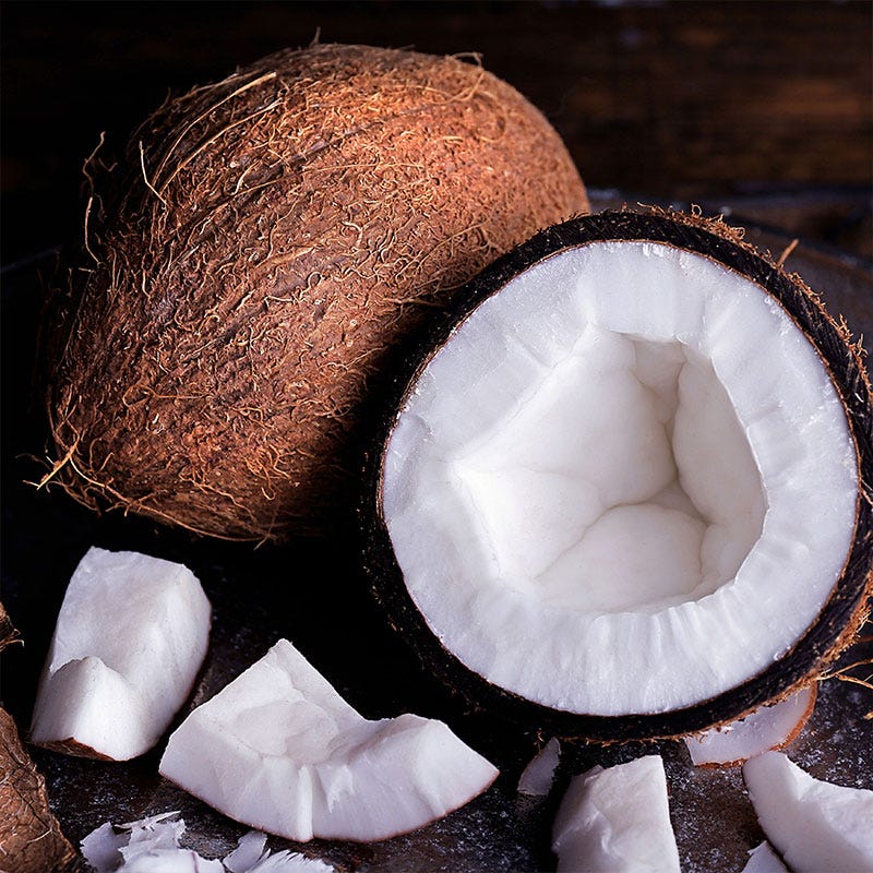 One whole coconut and a broken fresh coconut with bright white flesh