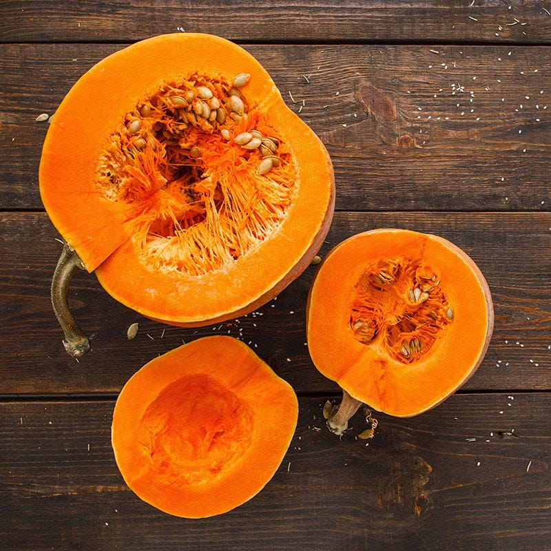 Three bright orange hirloom pumpkins cut in half showing their seeds