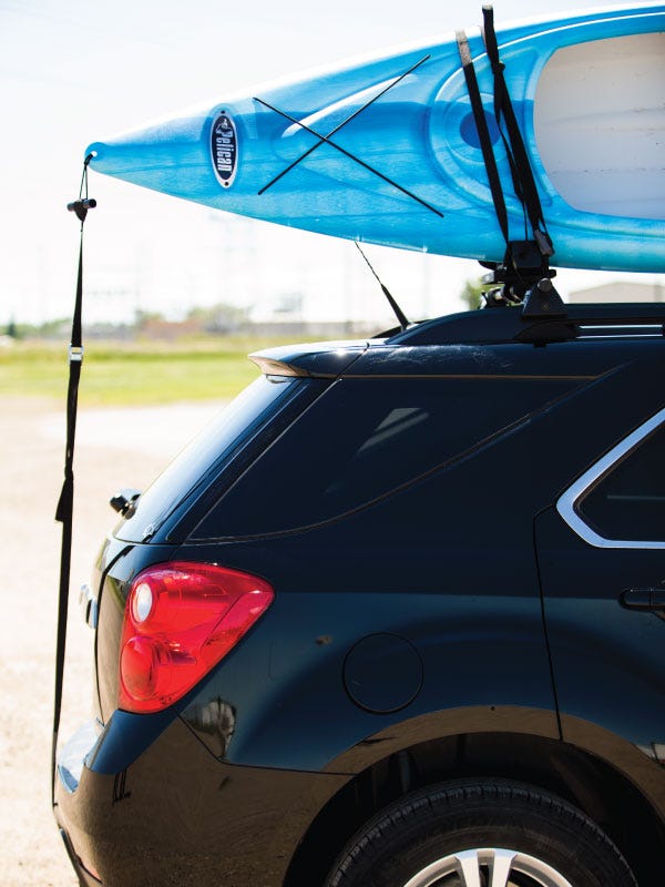 A blue Perception sit-in kayak secured on top of a black SUV