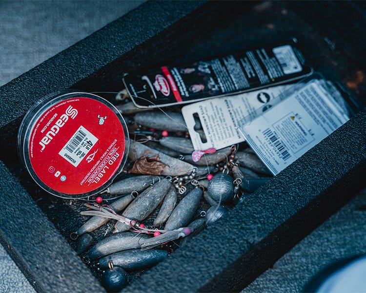 container of miscellanious fishing weights, lures, and seaguar red label line 