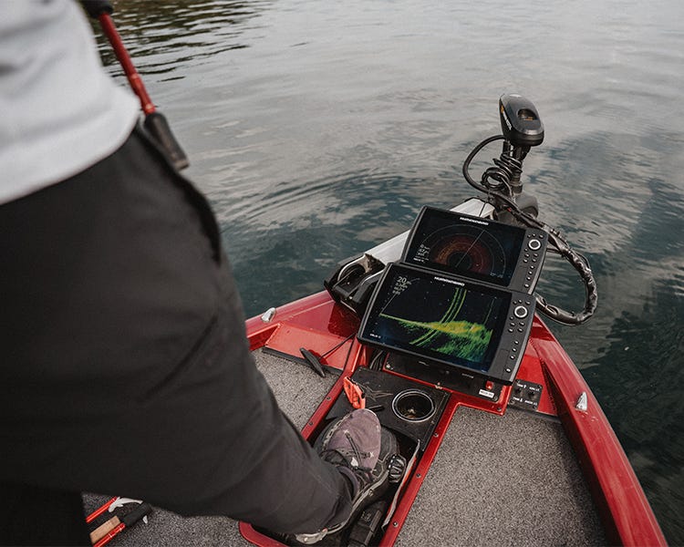on the bow of the boat, running the trolling motor with his foot, looking at his humminbird fish finder