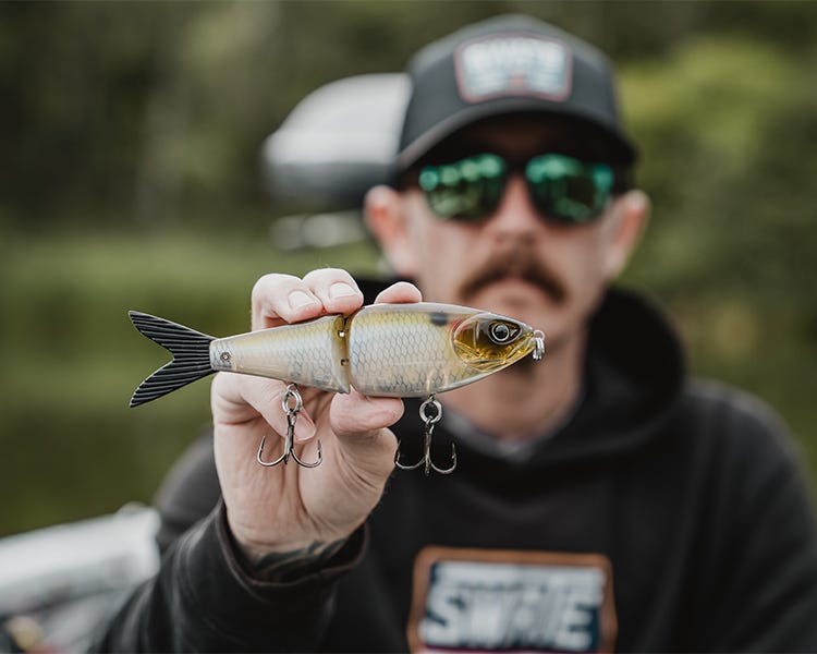 chris sitting on the deck of his boat holding up the strike king hogfather glide bait