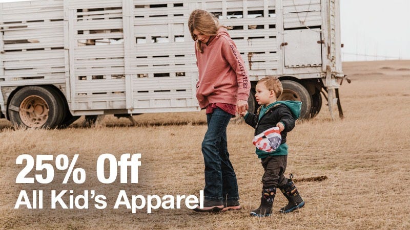 A young girl and a small boy walk hand-in-hand across a grassy field in front of a white livestock trailer, both dressed in casual clothes; large white text on the image reads "25% Off All Kid&rsquo;s Apparel."