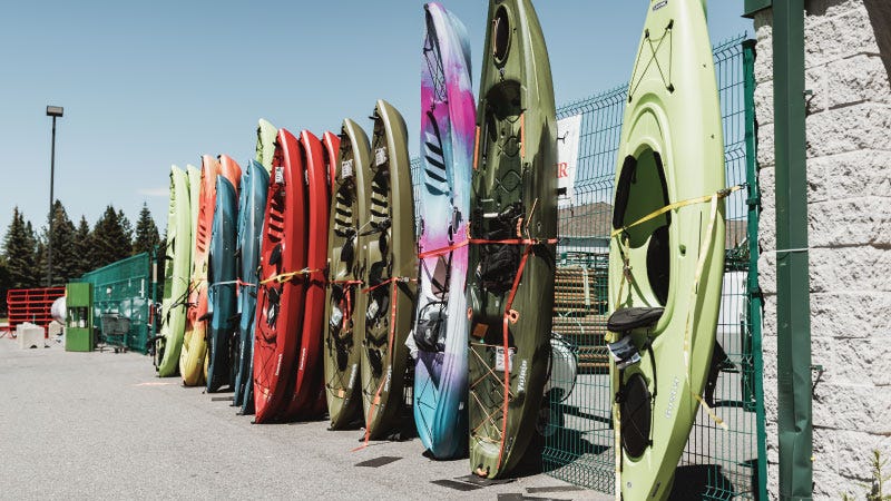 A large selection of kayaks outside against a fence at North 40 Outfitters