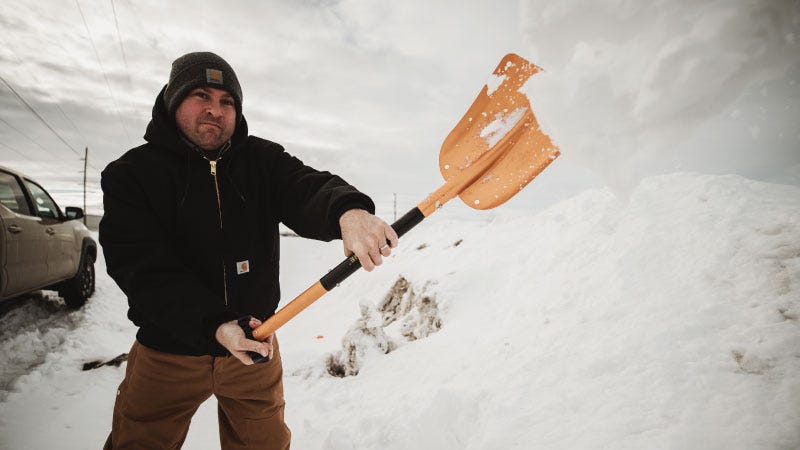 A man shovels snow on the side of the road during winter