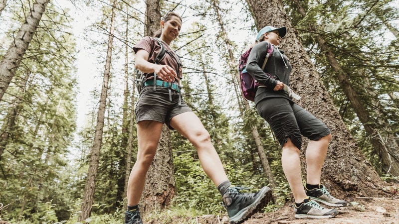 Wide angle image from low vantage point. Two women hike through the Montana wilderness.